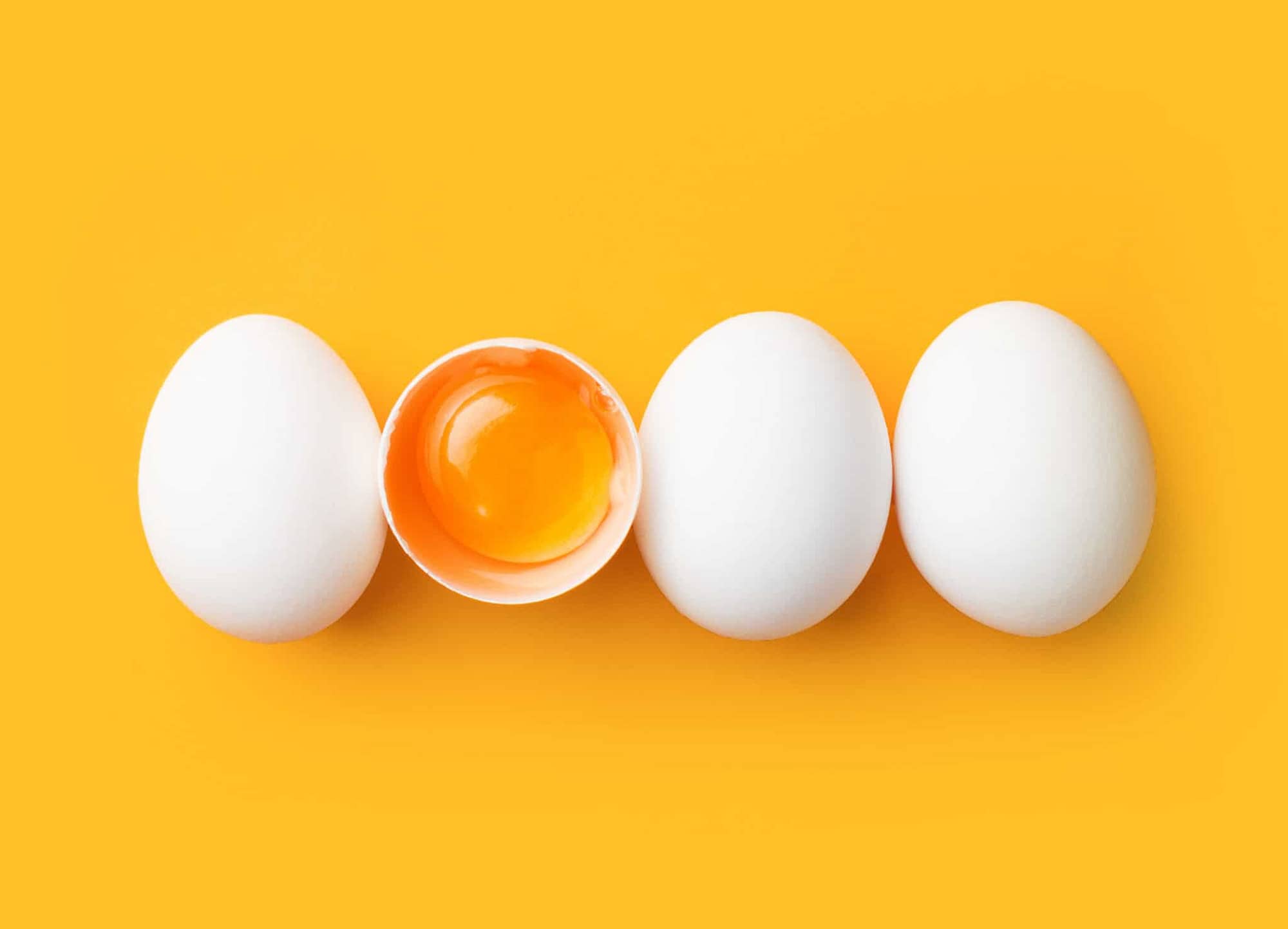 Egg yolk in egg shell with 3 other eggs