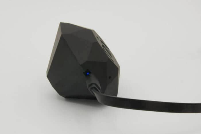 The Nix Pro is shown with its charging cable plugged in. A blue light is visible.