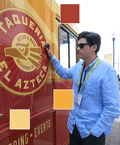 An individual scans the red, gold, and yellow brand of a taco truck
