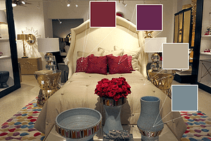 A showroom featuring a bed with bright red pillows and soft blue vases sitting on a table in front