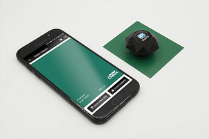 The Dulux device is scanning a green metal swatch, the results are displayed on a phone